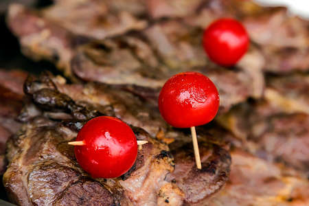 Pieces of steak decorated with tomatoes fixed on toothpicks.の写真素材
