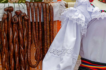 Romanian traditional sausages hanging on a fence, in a setting with specific costumes from Maramures, Romania.の写真素材