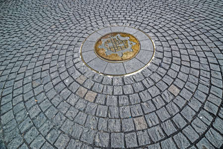 Background with cobblestone, sitting in a circle and having in the middle the symbol of Timisoara, Romania, representing map of medieval fortress made of metal.の写真素材