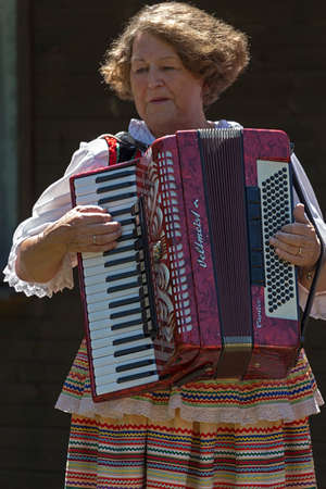 ROMANIA, TIMISOARA - JULY 10,2016: Old woman singer at accordion from Poland in traditional costume present at the folk festival "International Festival of hearts" organized by the City Hall Timisoaraのeditorial素材