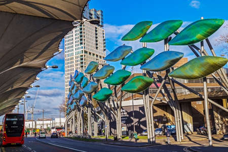 LONDON, ENGLAND - NOVEMBER 30, 2017: Futuristic signs outside Westfield mall in Stratford. Central bus stop with commuters. Red double deckers in background.のeditorial素材