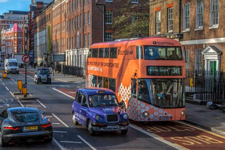 LONDON, UK - NOVEMBER 28, 2017: Typical street in London, with old traditions and new together. Double decker bus, retro-style taxis and new limousine. Old and new architecture.のeditorial素材