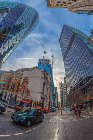 LONDON, ENGLAND - NOVEMBER 27, 2017: Wide angle shot of one street with skyscrapers in Central London, including Gherkin and Lloyd's towers, building in construction, typical taxi and people.のeditorial素材