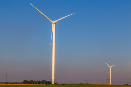Wind turbine set on an agricultural land, generating electricity on blue sky.