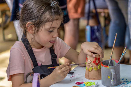 TIMISOARA, ROMANIA - JUNE 1, 2018: Little girl who paints ceramic funny objects. Workshop organized by the City Hall Timisoara with the occasion of the International children Day.のeditorial素材