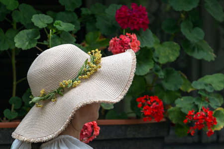 Woman with straw hat on a flower background.の写真素材