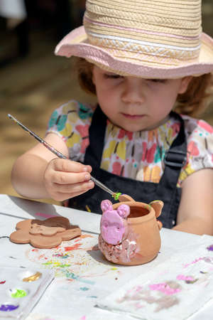 TIMISOARA, ROMANIA - JUNE 1, 2018: Girl who paints funny objects from ceramic. Workshop organized by the City Hall Timisoara with the occasion of the International children Day.のeditorial素材