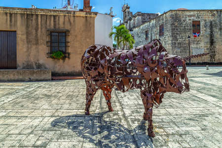 SANTO DOMINGO, DOMINICAN REPUBLIC - MARCH 13, 2020: Sculpture of an iron bull in front of the building museum of the Royal Houses and near famous Sundial. Modern art.のeditorial素材