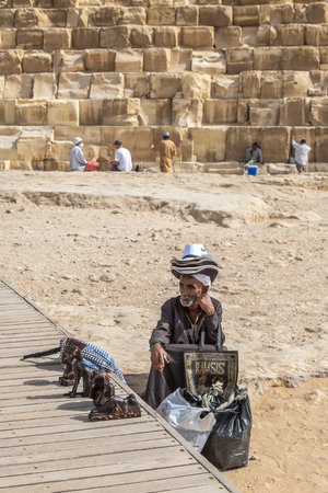 Giza Necropolis, Egypt - April 26, 2022: Old Bedouin man dressed in traditional clothes, sell...