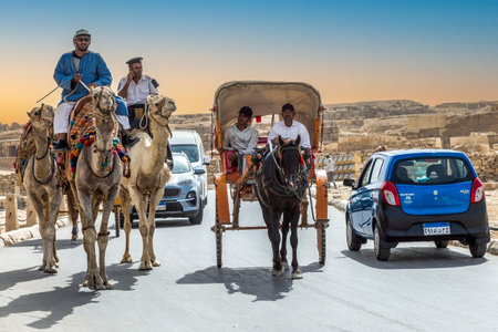 Giza Necropolis, Egypt - April 26, 2022: Funny specific traffic with camels, jumpers, cars, Bedouins...