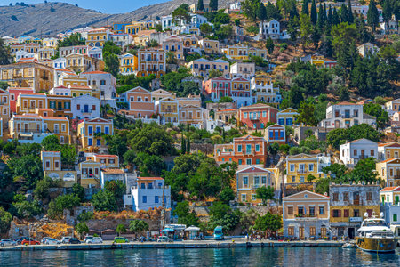 SYMI, GREECE - JULY 3, 2022: Symi harbour, with colorful neoclassical mansions covering the slopes...