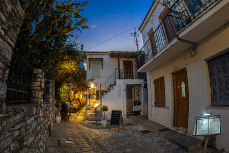 SKIATHOS TOWN, SKIATHOS ISLAND, GREECE - AUGUST 22, 2023: Evening view of the narrow streets, full of traditional taverns, in the Greek Mediterranean architecture of the old town.のeditorial素材