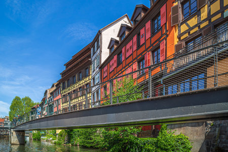 STRASBOURG, ALSACE - MAY 4, 2023: Passerelle des Anciennes-GlaciÃ¨res with row of buildings in typical Alsatian medieval architecture along the Canal du Faux-Rempart.のeditorial素材