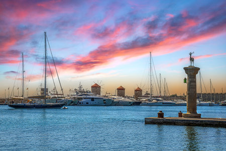 RHODES, GREECE - JUNE 29, 2022: Afternoon view with the Mandraki Marina Port, symbolic deer doe statues where the Colossus of Rhodes once stood, Windmills and yachts.のeditorial素材