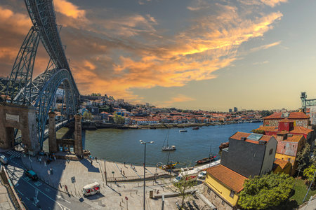 PORTO, PORTUGAL - APRIL 11, 2024: View with Dom Luis I Bridge over Douro river in sunset light and old town pier architecture with multi-colored houses in Porto Ribeira along Cais da Ribeira.のeditorial素材