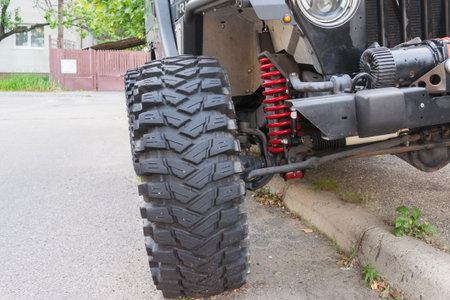 Detail of offroad vehicle showing big tire and red coil suspension