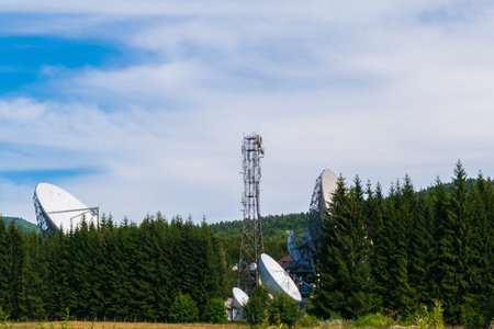 Big satellite dish antennas hidden in green pine tree forest. Satellite Communication Center in...