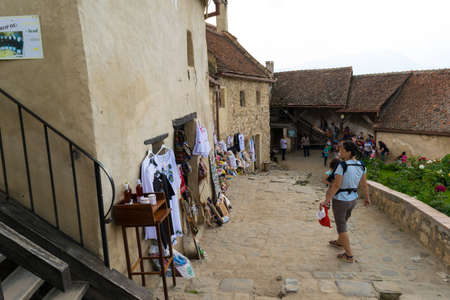 Rasnov, Brasov, Romania - June 15, 2019: Tourist walking thru Rasnov Fortress courtyard admiring souvenirs shops.のeditorial素材