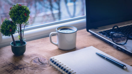 Office desk window notebook laptop coffee cup
