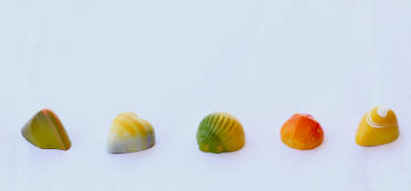 Chocolate bonbons with fruit flavours decorated with yellow, orange, green and white colorの写真素材