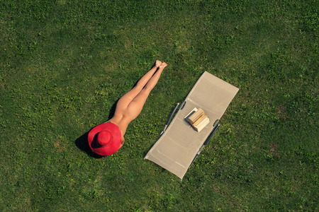 Woman lying on the grass near sunbed with bookの写真素材