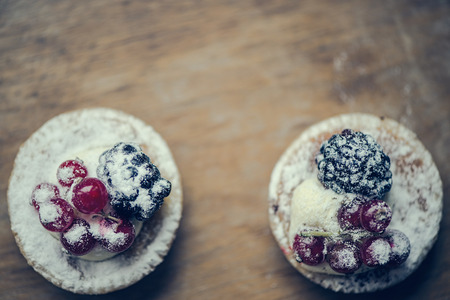 Pastry tarts with blackberries and red currants on a wooden boardの写真素材