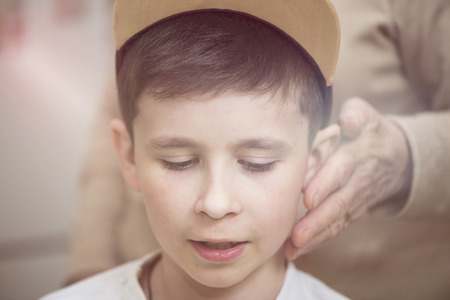 Grandmother's hand strokes the boy's face. Grandmother and grandson. The concept of the familyの写真素材