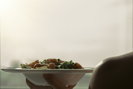 Female hands hold a plate with shrimp salad. The concept of eating and healthy lifestylesの写真素材