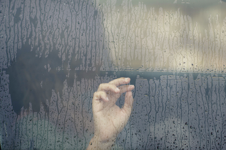 Hand of the woman in the car window with rain drop. Loneliness and depression concept. Psychologyの写真素材