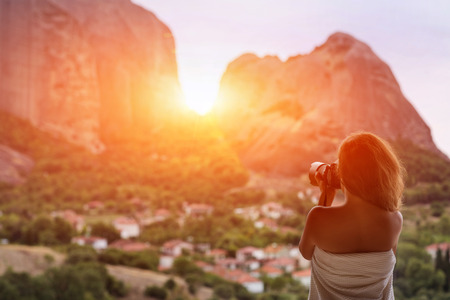 Female in blanket with camera on the balcony take a picture sunset in Meteora, Greeceの写真素材