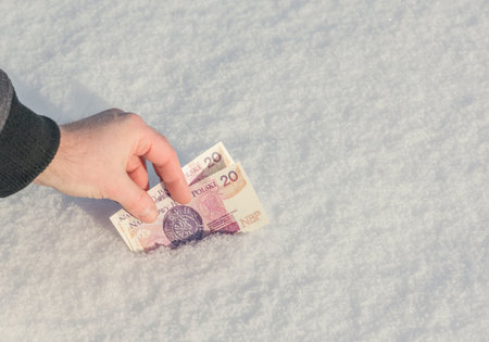 A man's hand for Polish zloty in the snow. Nice prize. Concept
