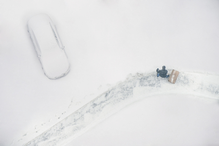 Janitor with a shovel cleans the snow of city street. View from aboveの写真素材
