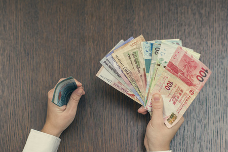 Female hand with a bundle of South-East Asia money. Currency of Hong Kong, Indonesia, Malaysia, China, Thai and Singapore. Travel concept. Exchangeの写真素材