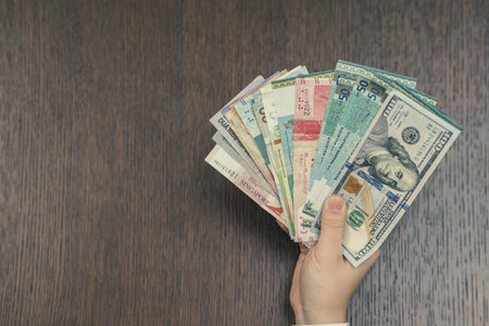 Female hand with a bundle of South-East Asia money. Currency of Hong Kong, Indonesia, Malaysia,...