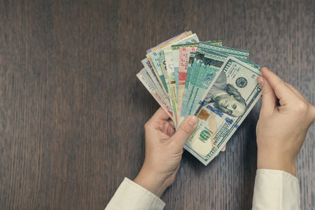 Female hand with a bundle of South-East Asia money. Currency of Hong Kong, Indonesia, Malaysia,...