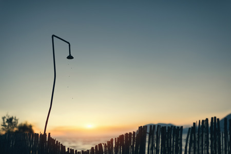 View of an old iron shower at the tropical beach on the sunset background. Silhouette of drops on the sunset background. A hot night at the tropical resortの写真素材