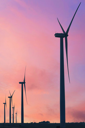 Vertical format of silhouettes of wind turbines on a farm in Iowa on a sunset sky background