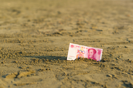 Banknote of value of of an China yuan in the the sand on the beach. Concept of cheap travel insuranceの写真素材