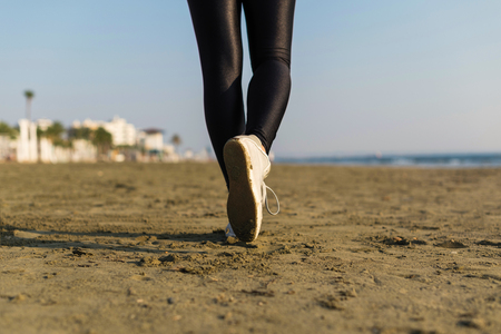 Bottom view of woman legs in the sport leggings and sneakers on the beach at the morning, healthy lifestyle.の写真素材