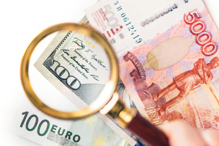 Hundred dollar under a magnifying glass on the backdrop euro and ruble banknotes. Ð¡oncept of the main international currencyの写真素材