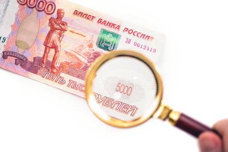 Banknote of five thousand russian rubles under a magnifying glass in the human hand. Concept
