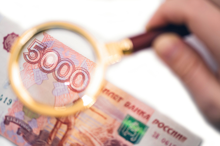 Banknote of five thousand russian rubles under a magnifying glass in the human hand. Conceptの写真素材