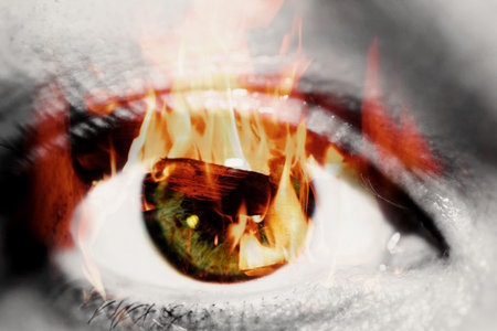 Double exposure of the closeup female eye and hot red coals from firewood in a fireplaceの写真素材