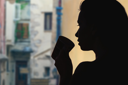 Female with cup of tea opposite a narrow streets of the old town of Verona. Italyの写真素材