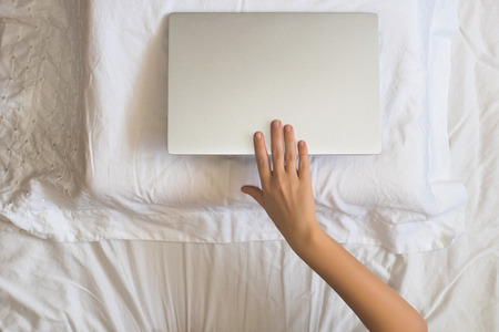 Girl lying with a laptop can't sleep and have to work late at night. Top viewの写真素材