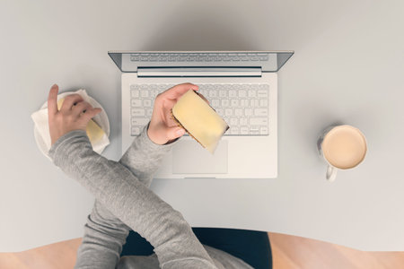 woman having lunch break at workplace with coffee and cheese sandwich. Top view