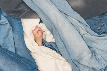 Girl hand showing fig sign in the ocean of jeans.  Conceptの写真素材