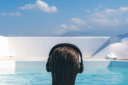 woman in the headphones listening to the  music bathing in a swimming poolの写真素材