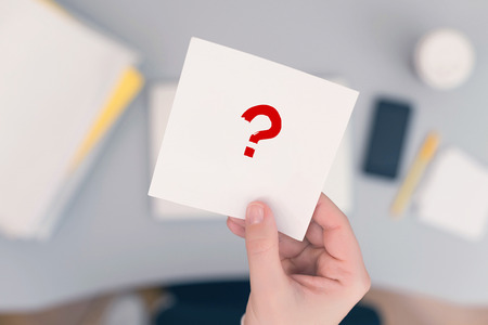 Woman clerk sitting at the office table and holding note sticker with question mark. Concept.の写真素材