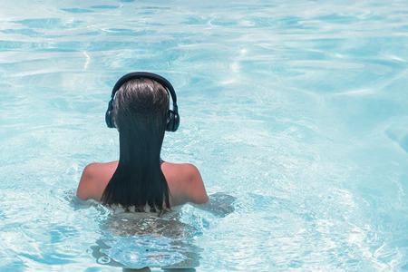 woman in the headphones listening to the  music bathing in a swimming poolの写真素材